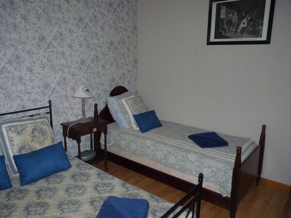 A bedroom with two single beds, a nightstand with a lamp, and a framed picture on the wall. - L'Arum Antique (Sainte-Catherine-de-Fierbois)