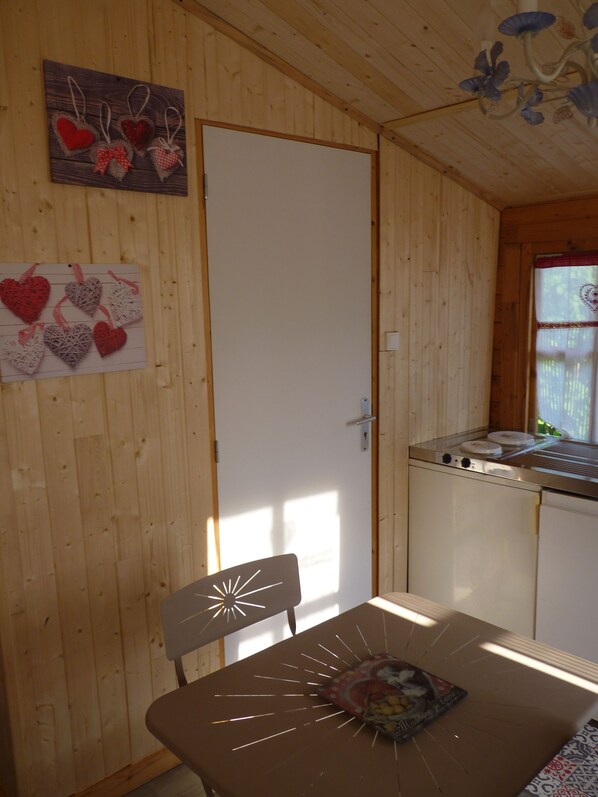 Interior de madera con una mesa de comedor, sillas, área de cocina y elementos decorativos con forma de corazón en la pared.