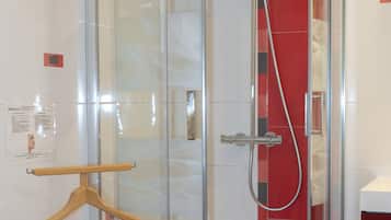 En dusch med glasväggar, utrustad med ett duschmunstycke som kan hållas i handen och ett annat duschmunstycke med en röd slang.
