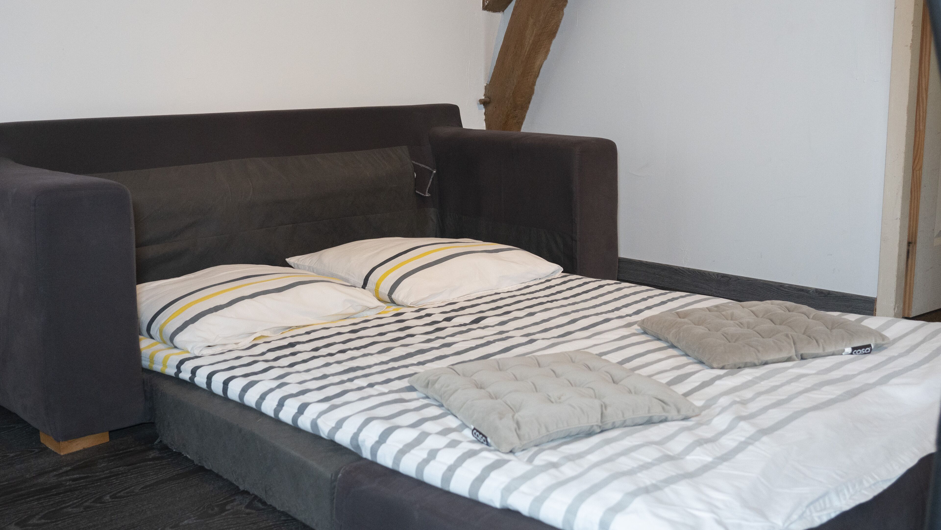 A bed with a striped bedspread, two pillows, and a single blanket.