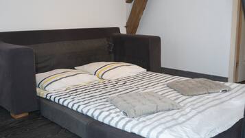 Un lit avec une couvre-lit à rayures, deux oreillers et une seule couverture.