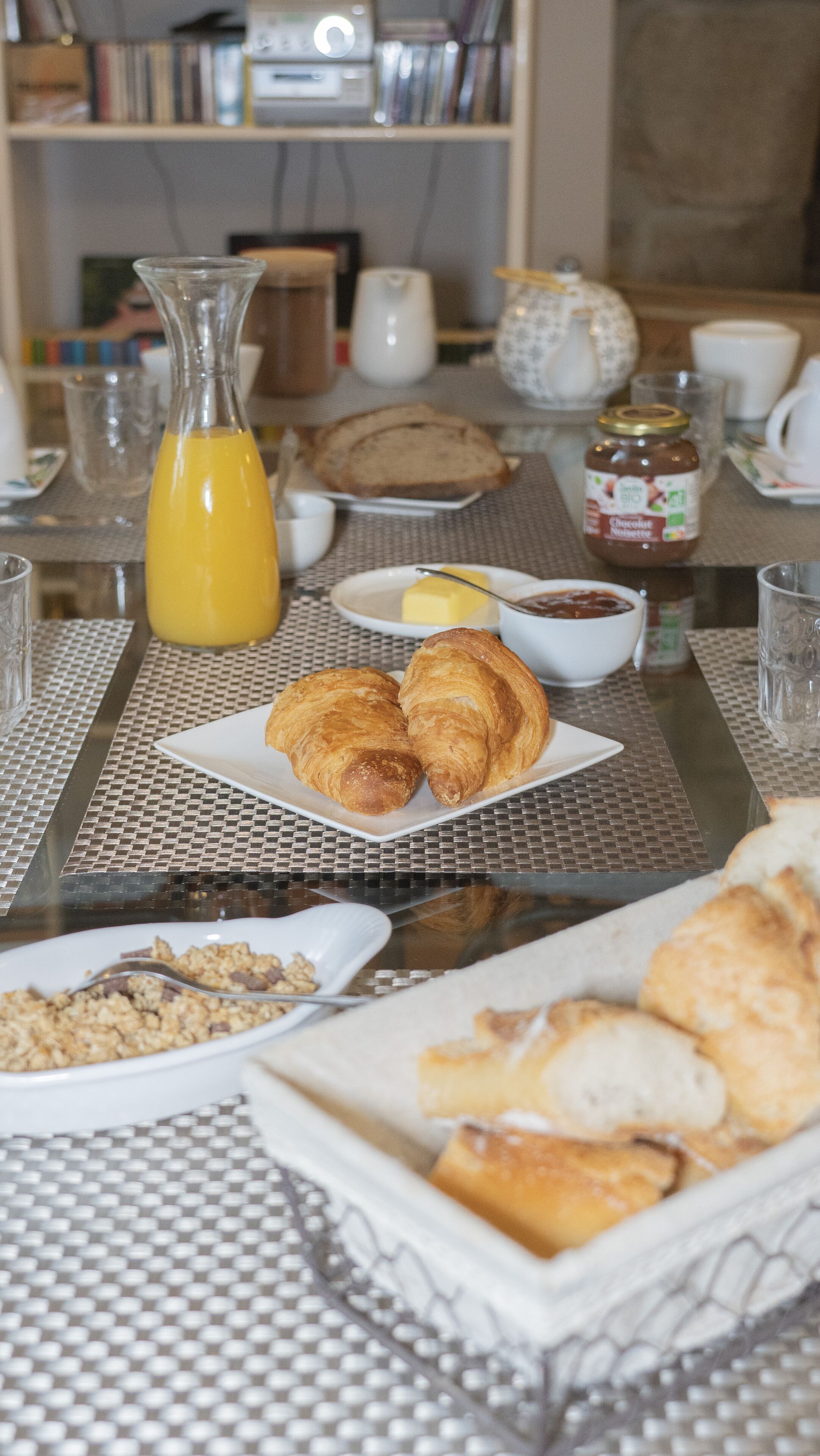 Une table de petit-déjeuner avec des croissants, un verre de jus d’orange et divers aliments pour le petit-déjeuner.
