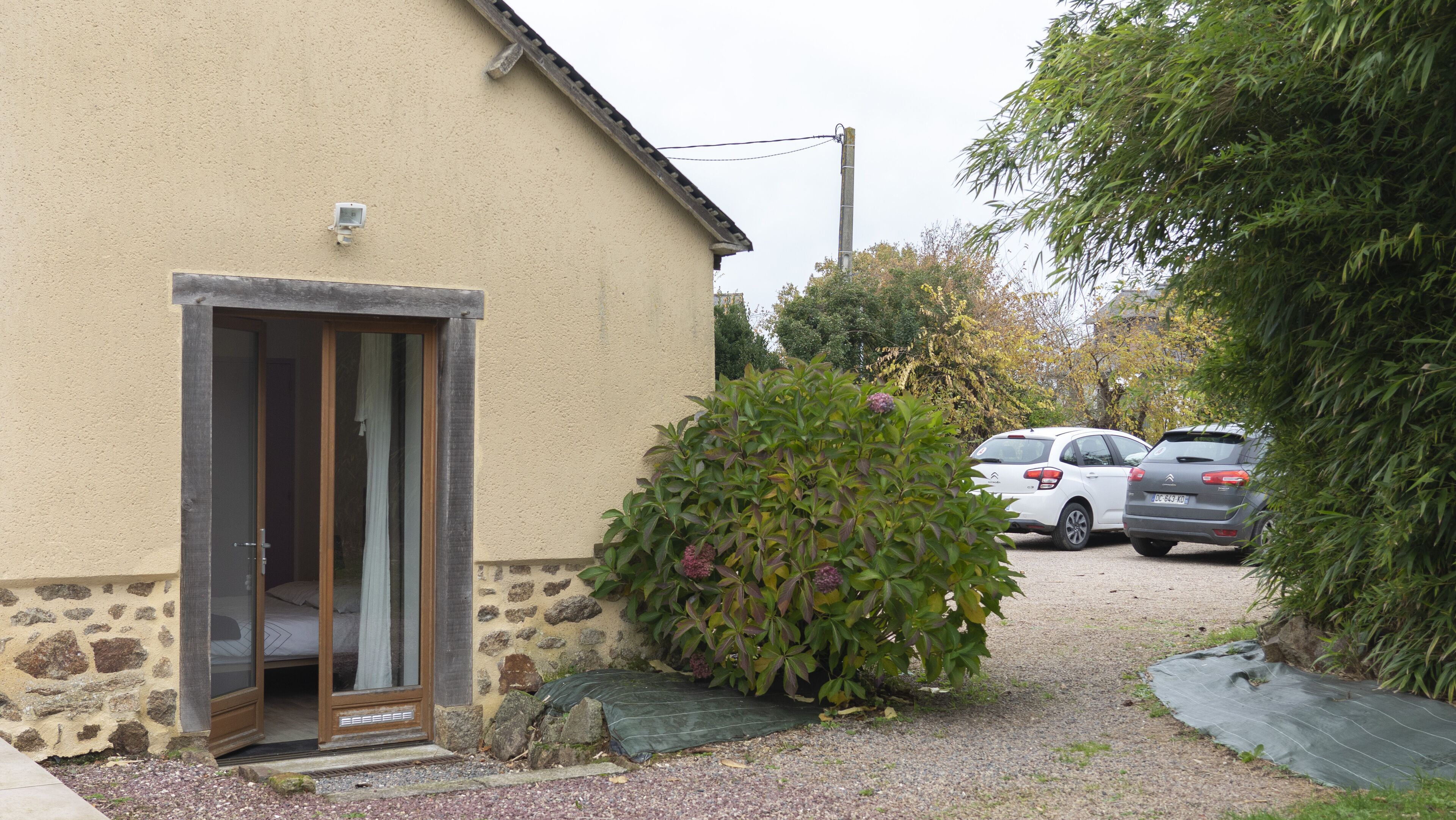 Una casa con fachada de piedra, puerta de madera y camino de entrada de grava.