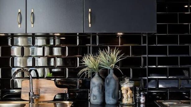 A modern kitchen with black cabinets, stainless steel appliances, and decorative vases on the countertop. - On Kloof Self Catering Apartment (Cape Town)