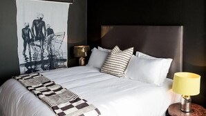 A neatly made bed with a striped blanket, white pillows, and a headboard. A lamp is on a bedside table. - On Kloof Self Catering Apartment (Cape Town)
