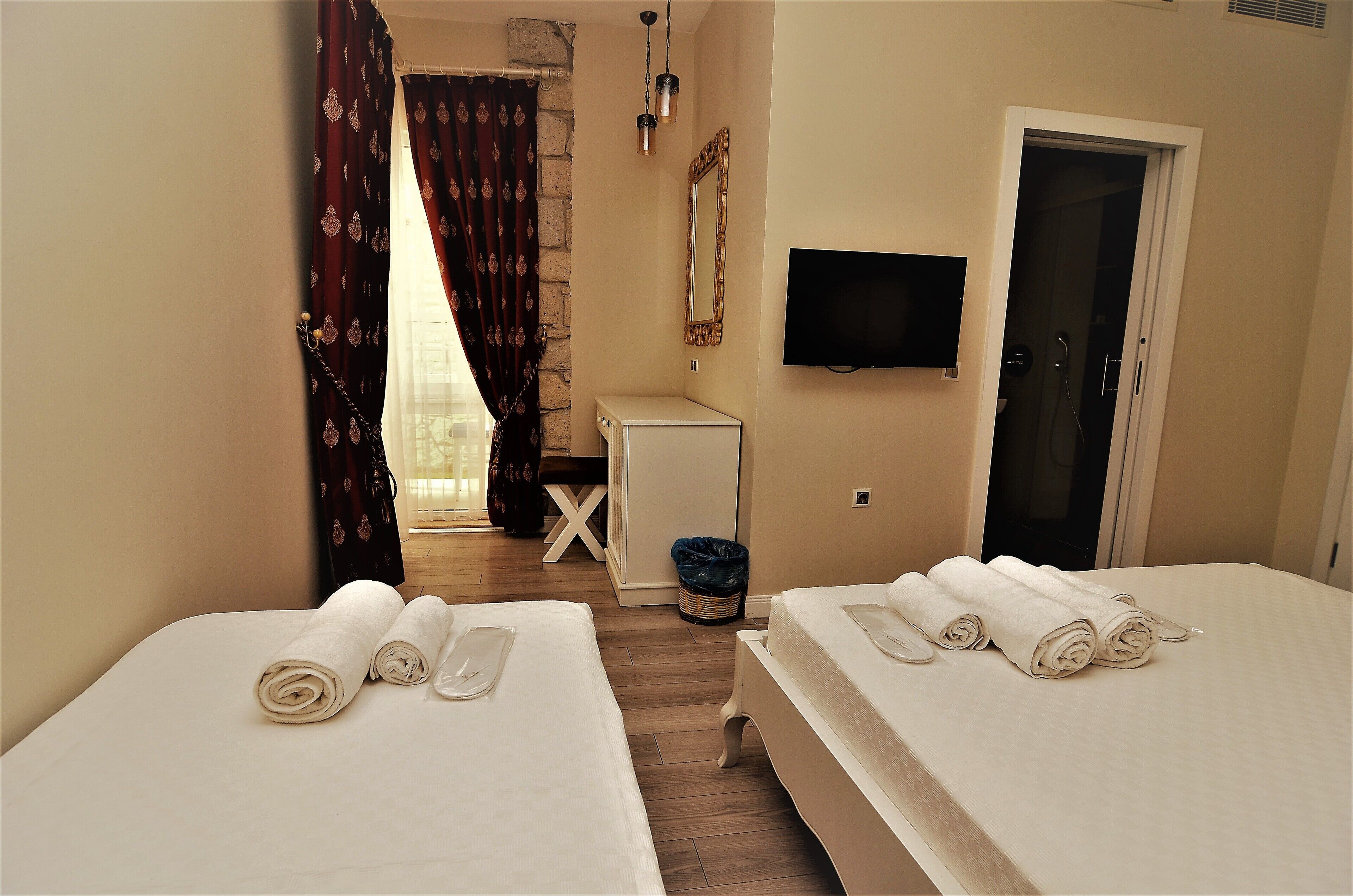 Habitación de hotel con dos camas, televisión, un escritorio pequeño y la puerta del baño.