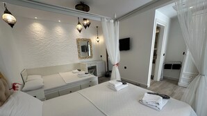 Ein Hotelzimmer mit einem großen Bett, einem Nachttisch, einem Spiegel und einem an der Wand befestigten Fernseher.