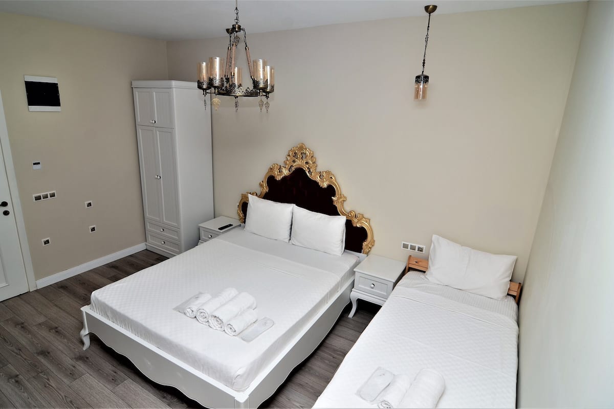Ein Hotelzimmer mit einem großen Bett, einem Kleiderschrank, einer Chandelüster und einem Nachttisch.