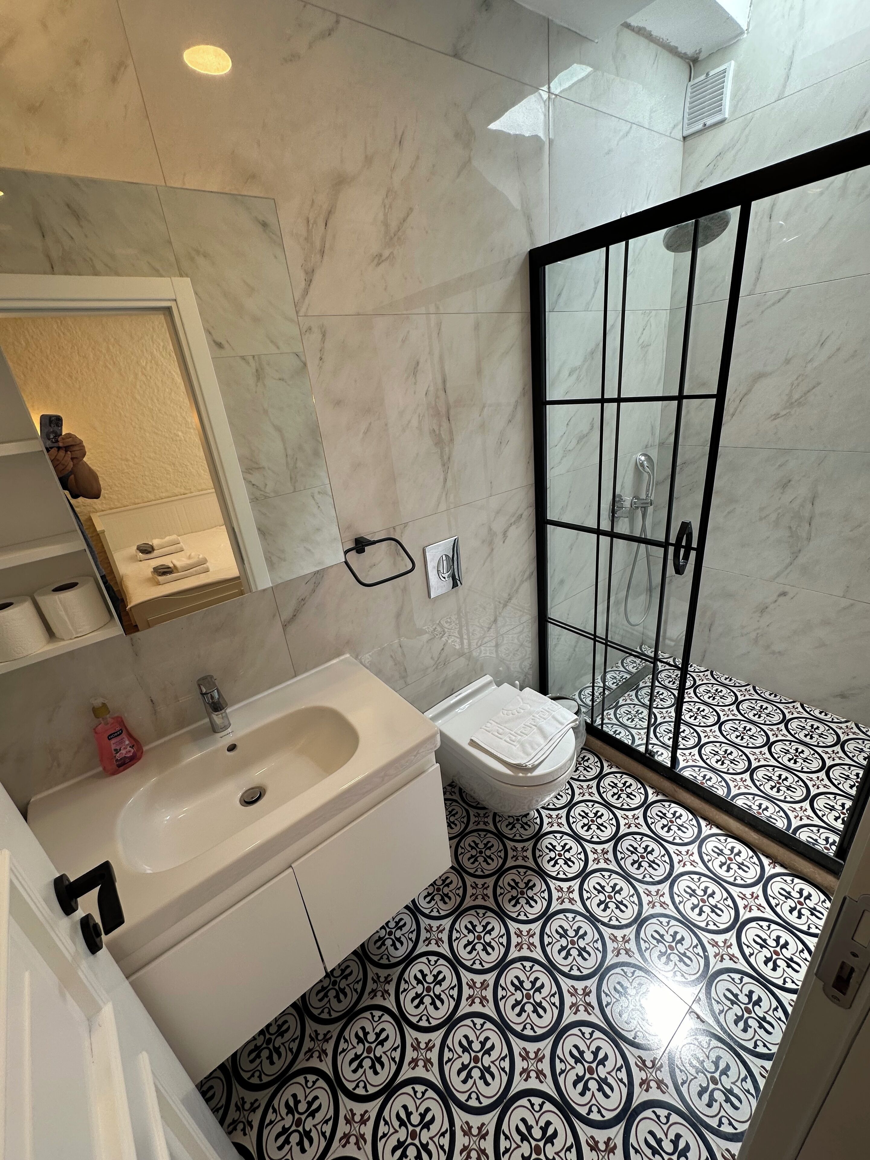 Un baño con lavamanos, inodoro y zona de ducha de mármol.