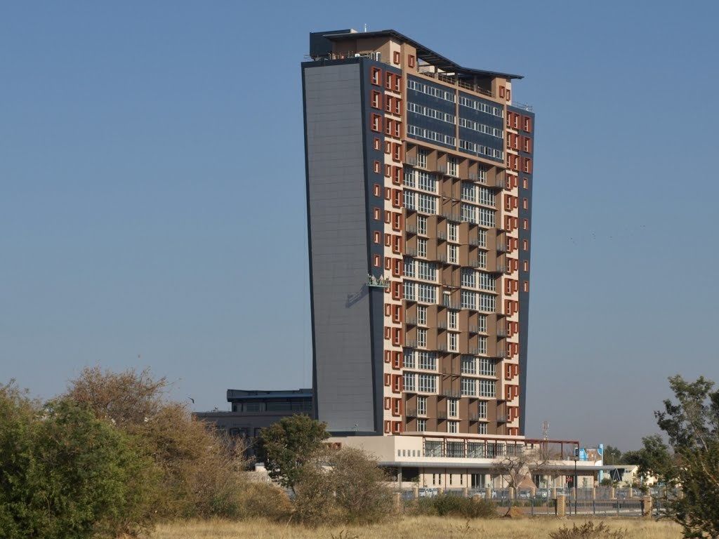 A tall, modern building with multiple balconies and a flat roof.