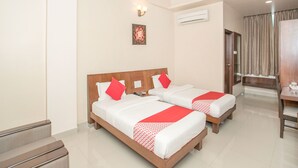 A hotel room with two beds, a ceiling fan, an air conditioning unit, a desk, and a chair. - OYO 490 Hotel Compact Maple Leaf (Bengaluru)