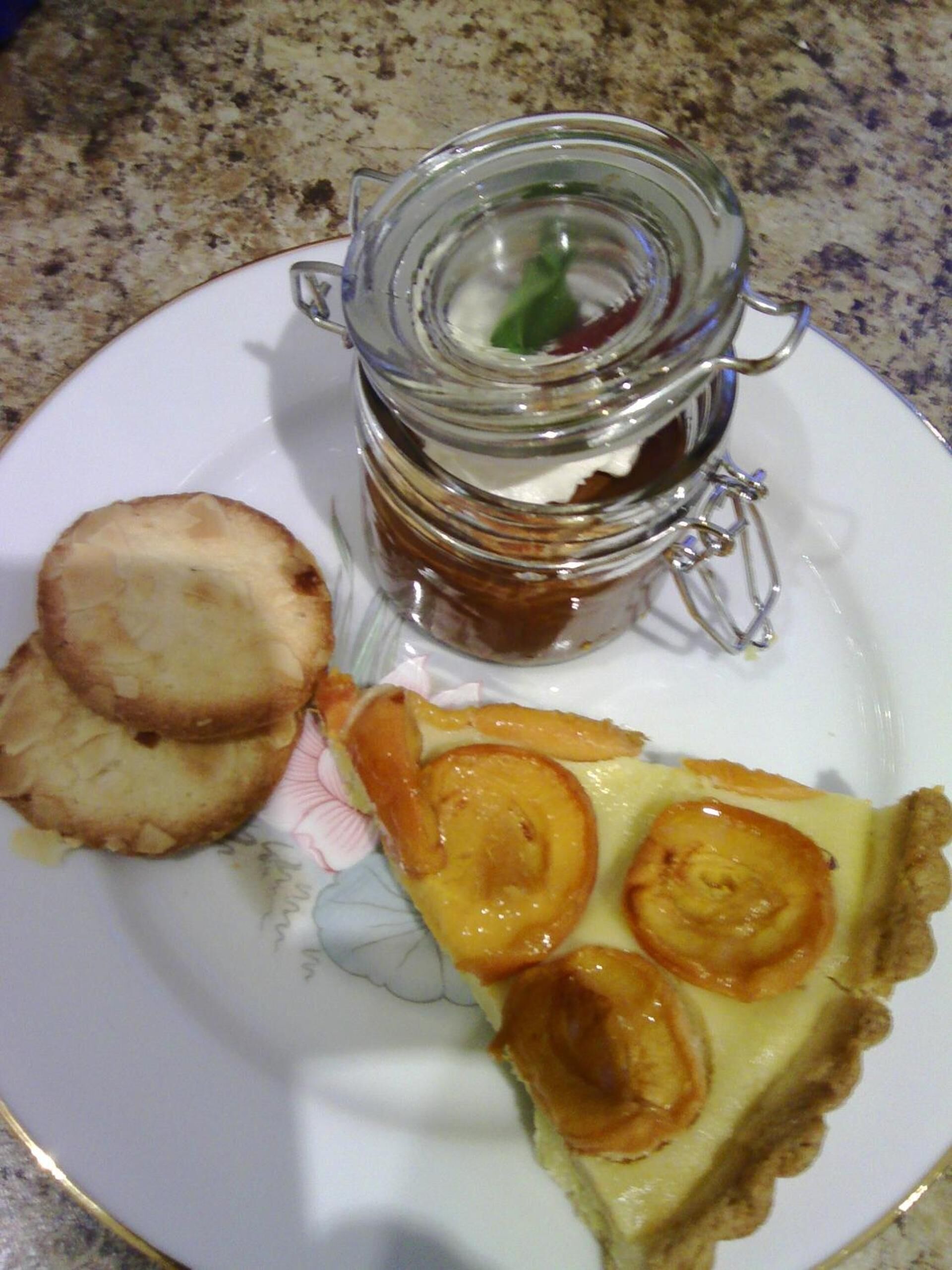 Un plato con una porción de quiche, un frasco pequeño de mermelada y dos galletas.