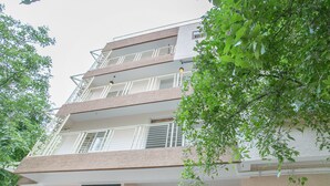 A multi-story building with balconies, a visible entrance, and surrounding greenery. - OYO 12045 Dollars Nest (Bengaluru)