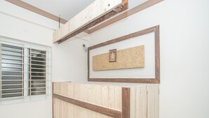 A reception desk with a wooden finish, a framed picture on the wall, and a window with blinds. - OYO 12045 Dollars Nest (Bengaluru)