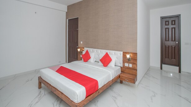 A modern bedroom with a large bed, wooden headboard, and a red accent pillow. - OYO 12045 Dollars Nest (Bengaluru)