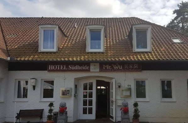 A two-story building with a tiled roof, a sign for HOTEL Südheide, and a smaller sign for Mr. Wu's Restaurant.