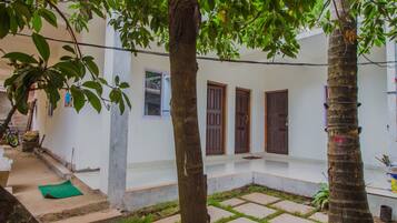 Stroll through this serene courtyard, featuring an entrance, paved tiles, and a natural tree trunk.