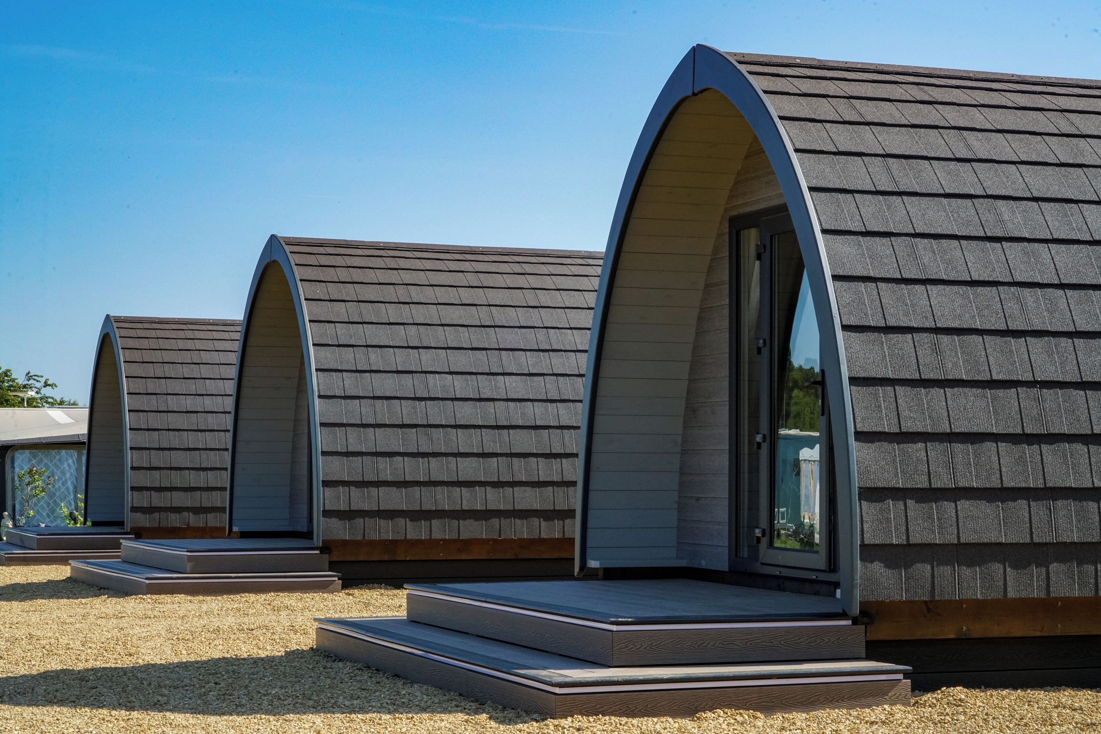 Een rij moderne, ronddakige accommodaties met een grindpad.