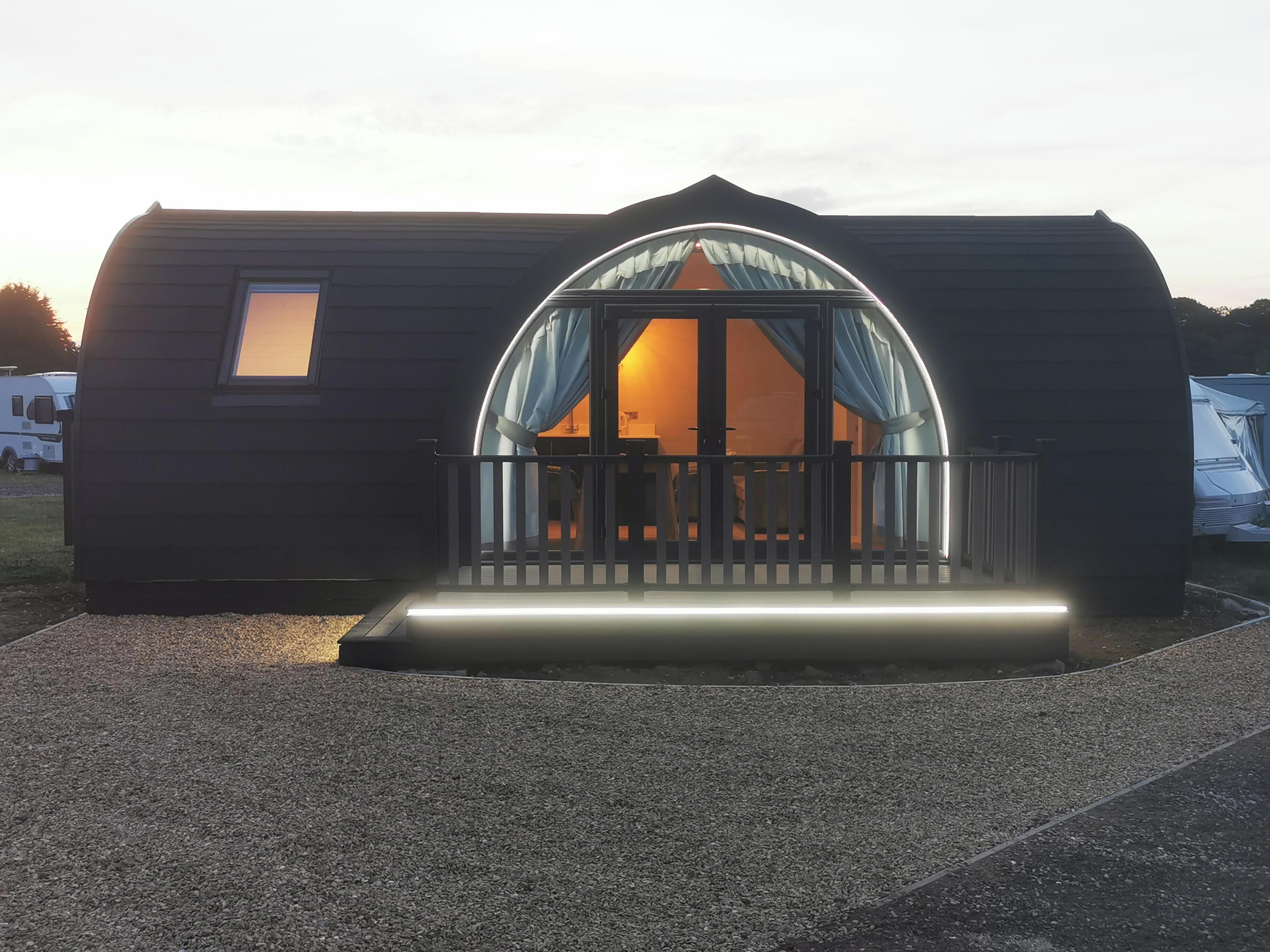 A small, dark-colored mobile home with a semi-circular window and a balcony.