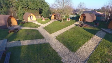 Un camping con varias cabañas de madera, senderos de grava y mesas de picnic.