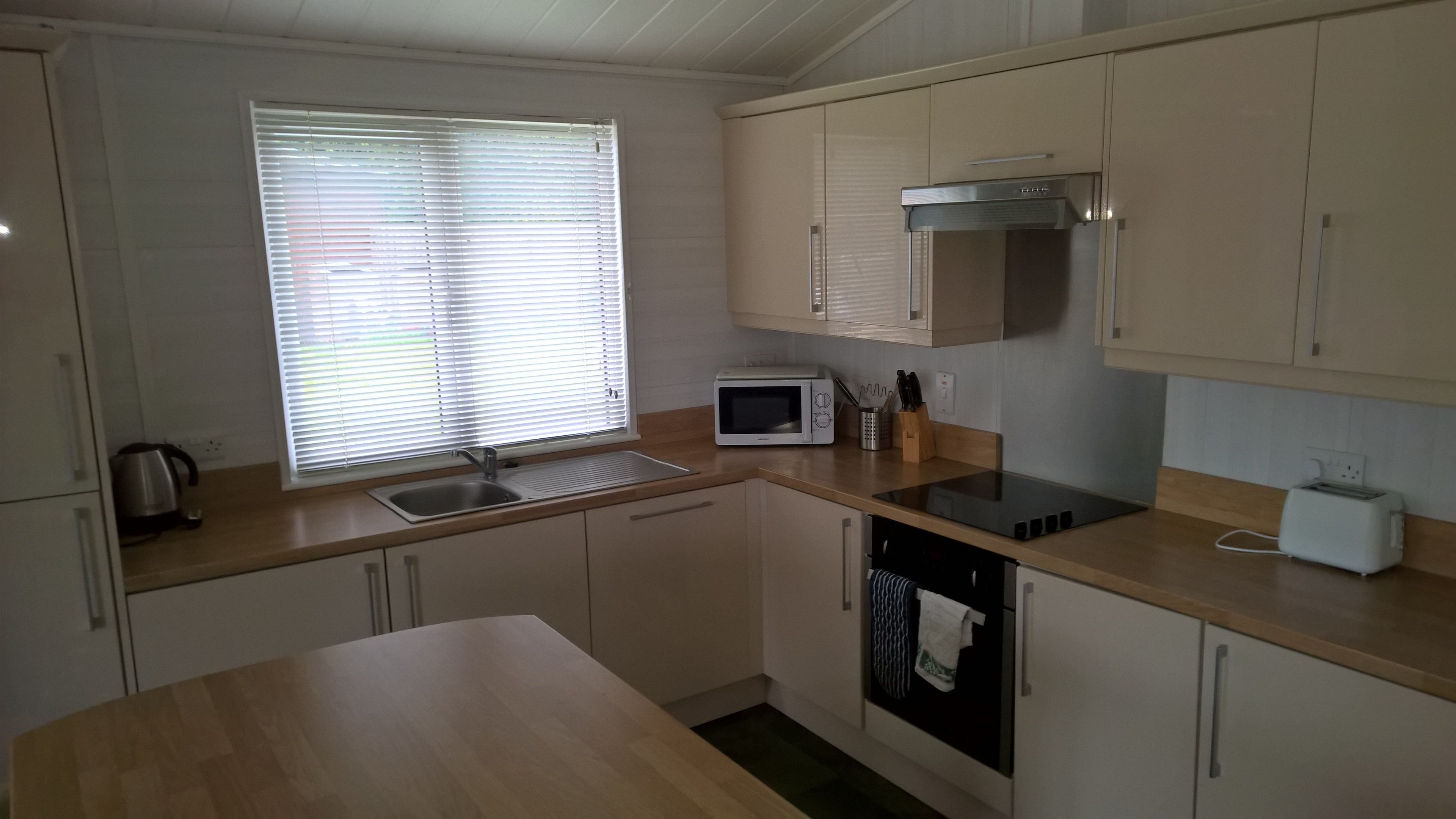 A compact kitchen with a sink, microwave, stove, and a toaster.