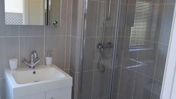 A modern bathroom with a glass-enclosed shower, a white sink, and a mirror above it.