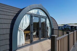 A modern building with a curved glass window and a wooden deck.