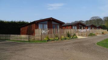 A row of wooden cabins with a gravel driveway and a wooden fence.