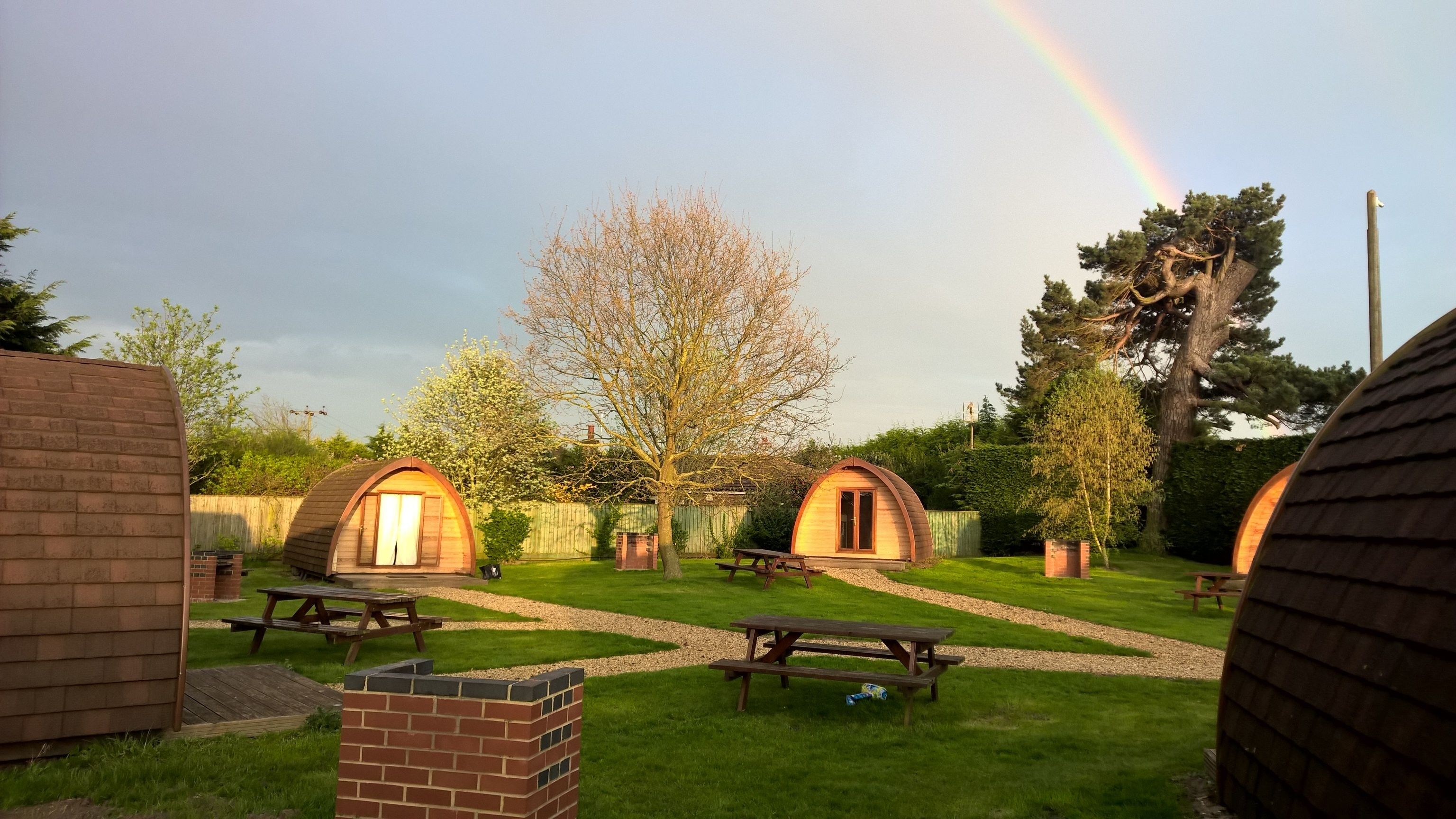 Un terrain de camping comprenant deux cabanes en bois en forme de dôme, des tables de pique-nique et une zone herbeuse.
