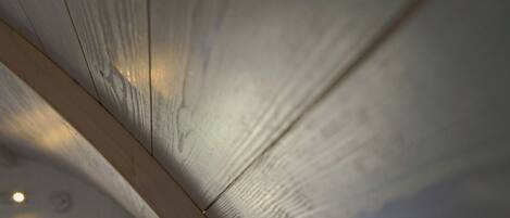 A close-up of a wooden ceiling with visible grain patterns and a light fixture.