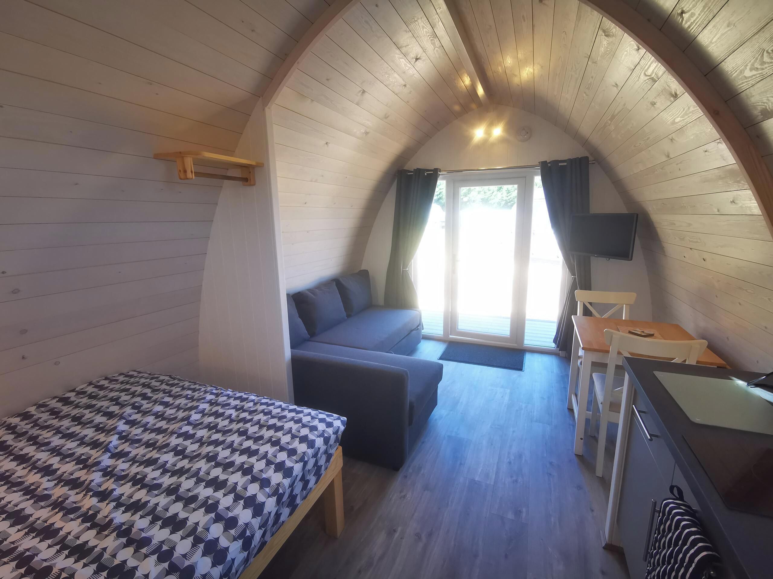 A cozy, single-room accommodation with a bed, sofa, and a small dining area.