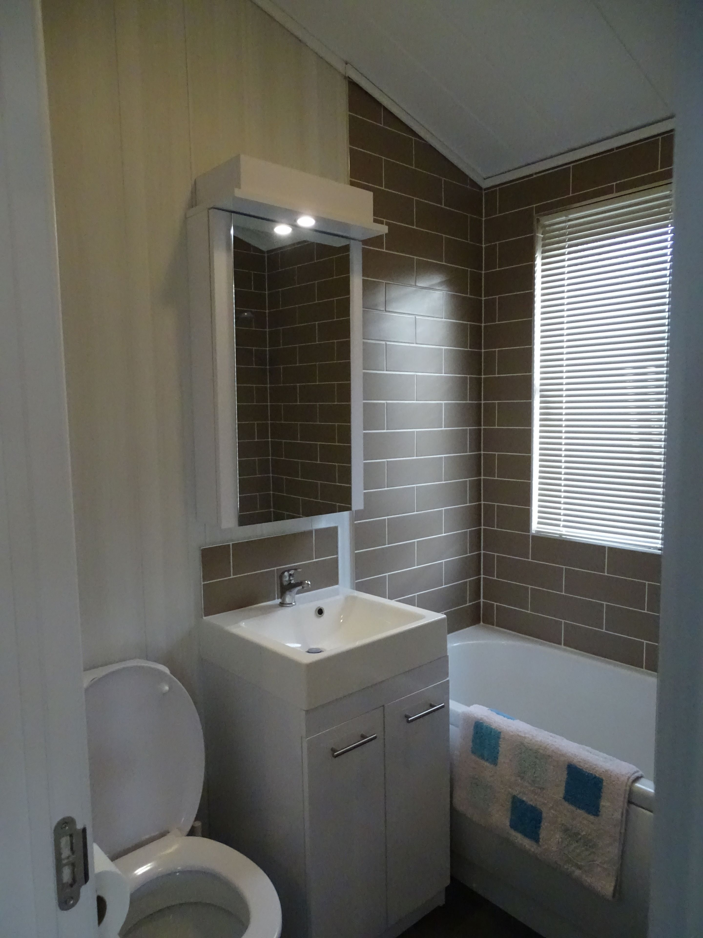 A bathroom with a toilet, sink, mirror, and bathtub.