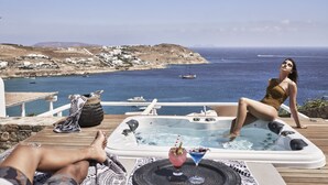 Een hottub op een houten terras met uitzicht op zee en boten.