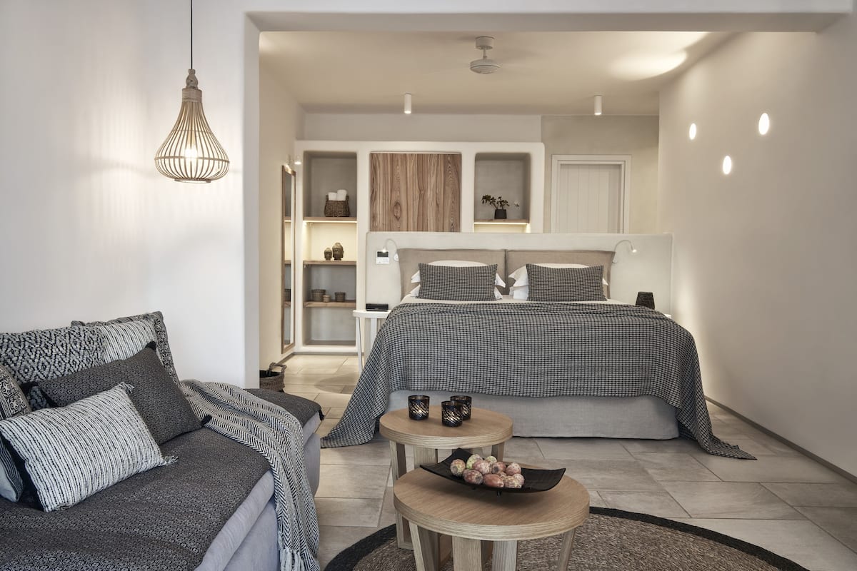 Een moderne slaapkamer met een groot bed, een bank en een klein houten tafeltje met fruit.