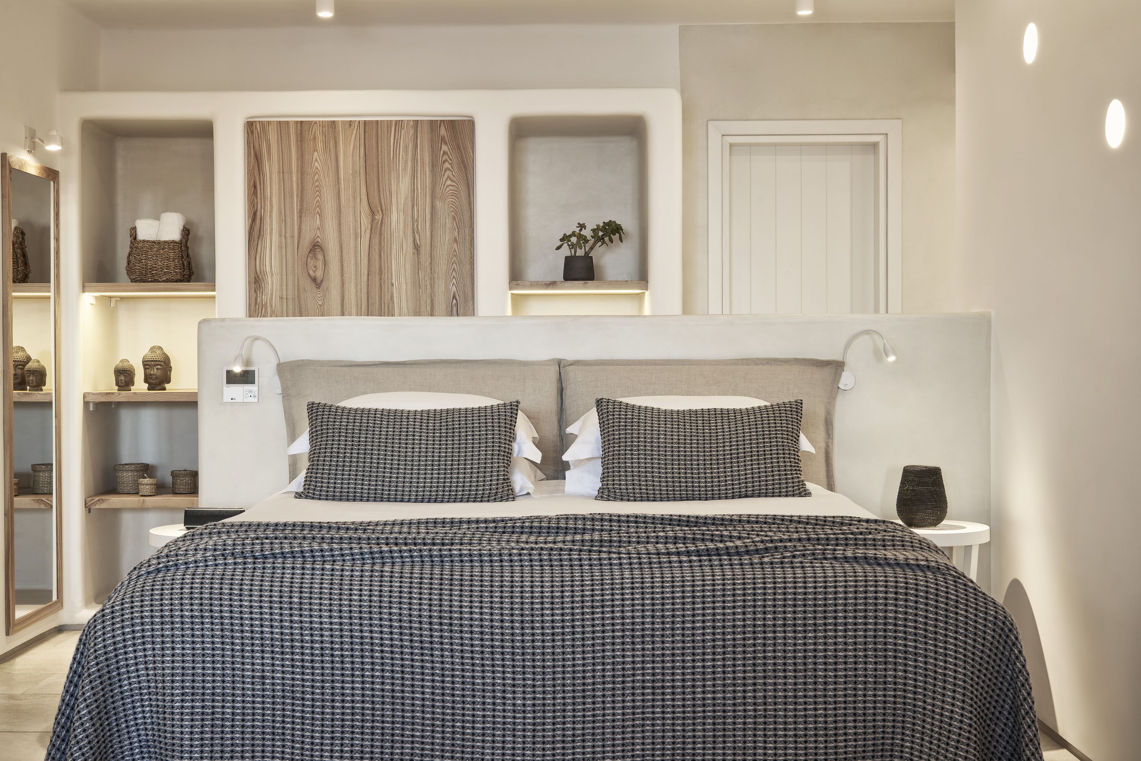 A bedroom with a large bed, two bedside tables, a mirror, and built-in shelving with decorative items.