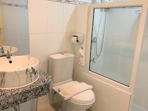 A bathroom with a marble sink, toilet, and a glass-enclosed shower. - Nan Panwa Hotel (Nan)