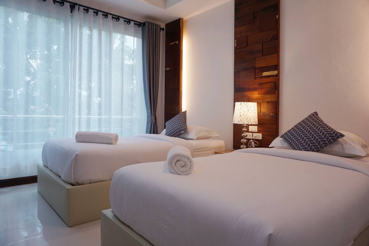 A hotel room with two beds, each with a pillow and a rolled towel.