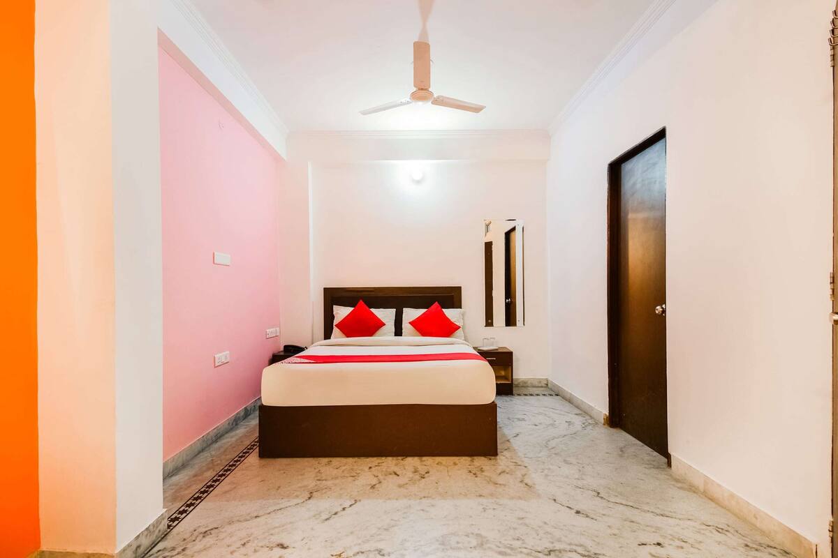 A bedroom with a bed, a ceiling fan, a nightstand, and a door.