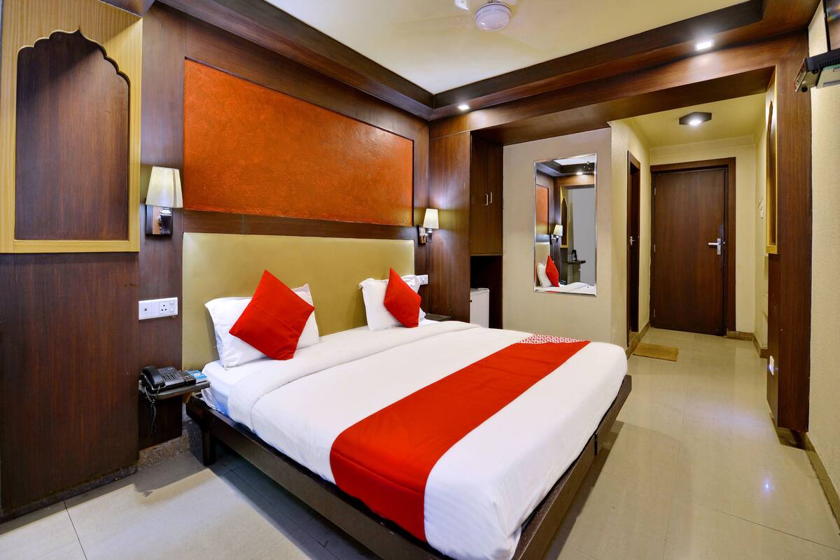 A hotel room with a large bed, a telephone, and a mirror on the wall.