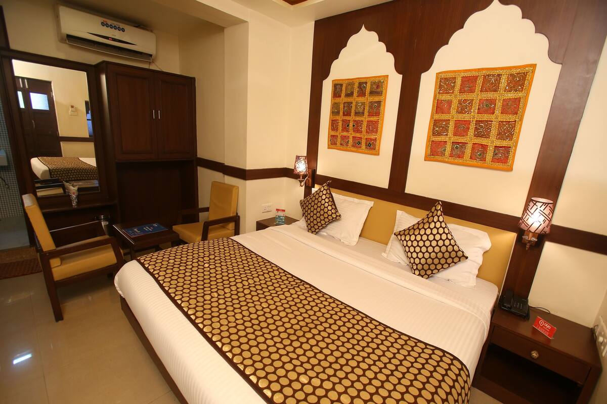 A hotel room with a large bed, a wardrobe, a desk, and a chair.