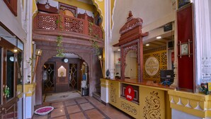 Un hall d’hôtel au design traditionnel, comprenant un comptoir d’accueil, un distributeur d’eau et une arche décorative.