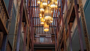 A multi-level atrium with a central decorative fountain, wooden railings, and hanging lamps. - Sunny V Hotel (Chiang Mai)