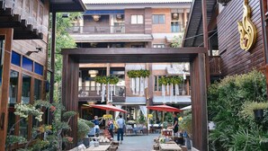 An outdoor courtyard with wooden structures, potted plants, and tables for dining. - Sunny V Hotel (Chiang Mai)