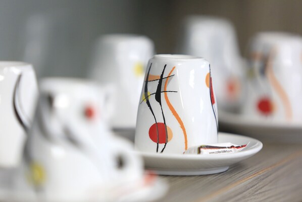 A close-up of a white ceramic cup with abstract designs, placed on a matching saucer.