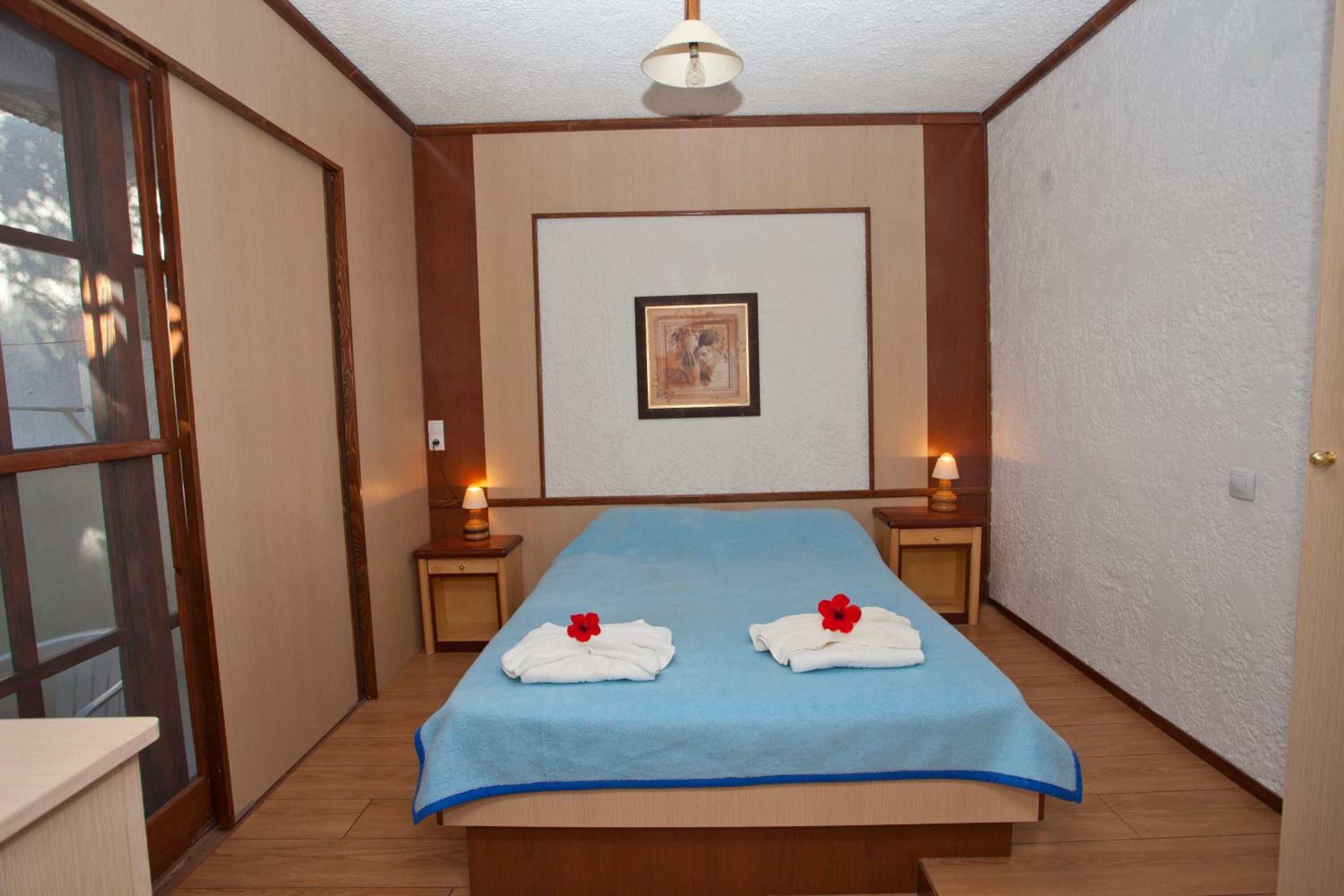 Camera d'albergo con un letto grande, due comodini con lampade, un quadro appeso al muro e una porta scorrevole a sinistra.
