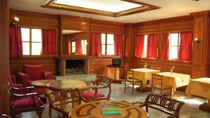 A room with wooden paneling, a fireplace, a television, and multiple seating areas with tables and chairs. - Damnoni Paradise (Agios Vasileios)