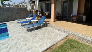 A swimming pool with blue tiles, surrounded by lounge chairs and umbrellas. - Villa Angela (Corfu)