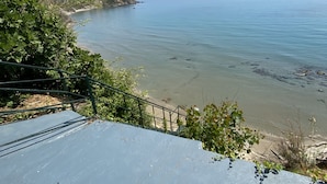 A coastal view with a clear sky, a sandy beach, and a rocky outcrop. - Villa Angela (Corfu)
