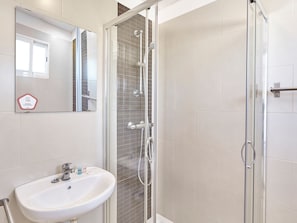 A bathroom with a glass-enclosed shower, a sink with toiletries, and a mirror. - Hostal Mas Ferrer (Cornella del Terri)