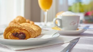 Lautasella croissantteja, lasissa appelsiinimehua ja pöydällä kahvikuppi.
